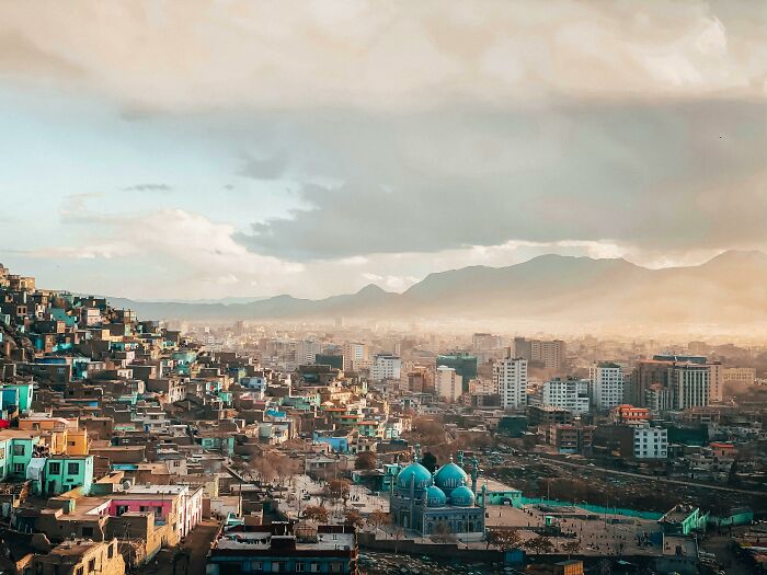 Aerial view of a cityscape with colorful buildings under a cloudy sky, showcasing elements of urban life and architecture.