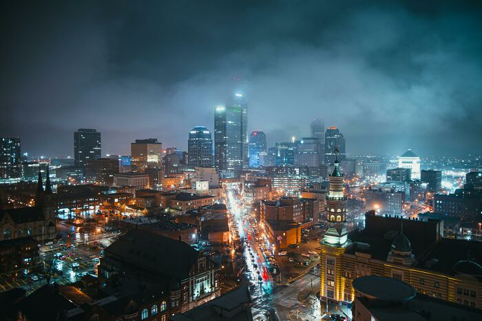 Night view of a city skyline with illuminated buildings and cloudy skies, highlighting worst city country trip experience.
