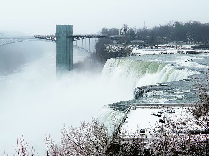 Snowy view of a city with a bridge and waterfall, possibly representing a challenging trip experience.