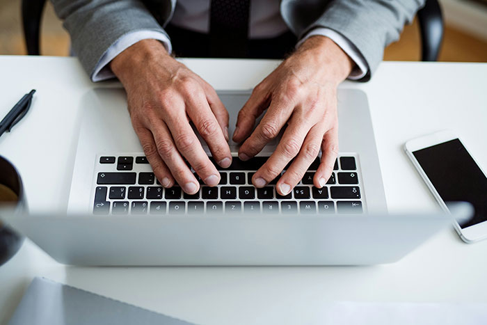 Close-up of hands typing on a laptop keyboard, associated with YesMadam firing controversy.