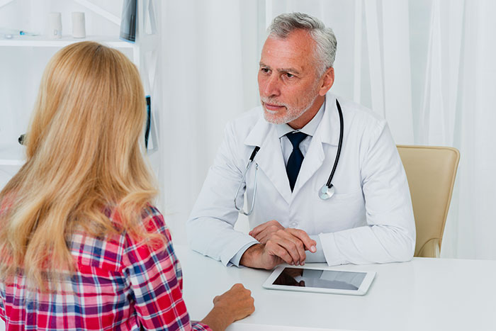 A woman discussing medical binder hack with a doctor at a clinic. A woman discussing medical binder hack with a doctor at a clinic.