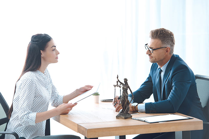 Man and woman in legal discussion over a family feud involving a family heirloom, sitting at a table with a justice statue.