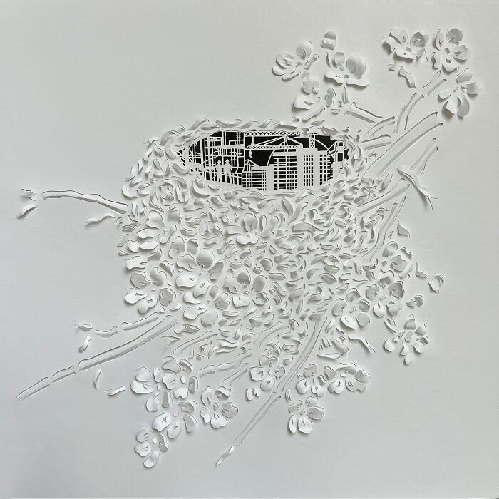 Intricate paper cut design depicting a tree-less scene in white with detailed branches and cityscape background.