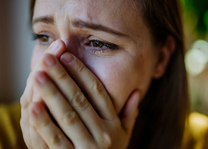Close-up of a woman looking distressed, holding her hands over her mouth, highlighting emotional tension in a wedding speech. Close-up of a woman looking distressed, holding her hands over her mouth, highlighting emotional tension in a wedding speech.
