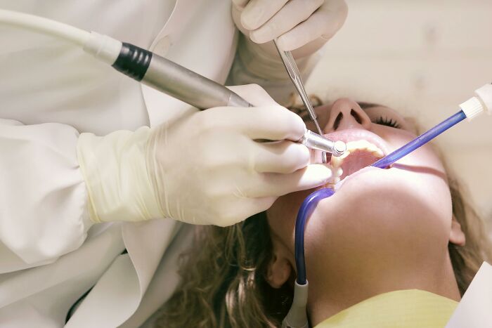 Dentist performing a procedure, using tools on a patient.