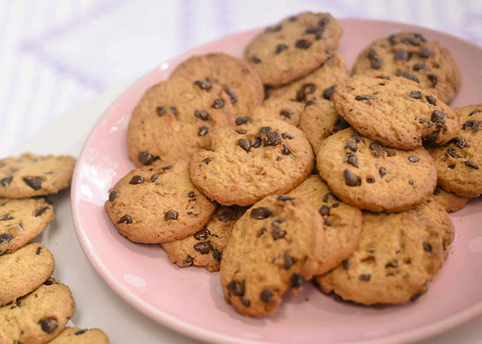 Plate of chocolate chip cookies, freshly baked and arranged on a pink dish; unique culinary display.
