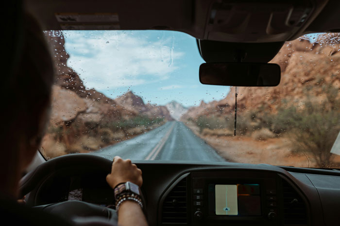 Driving through a scenic wet canyon road, viewed from inside a car.