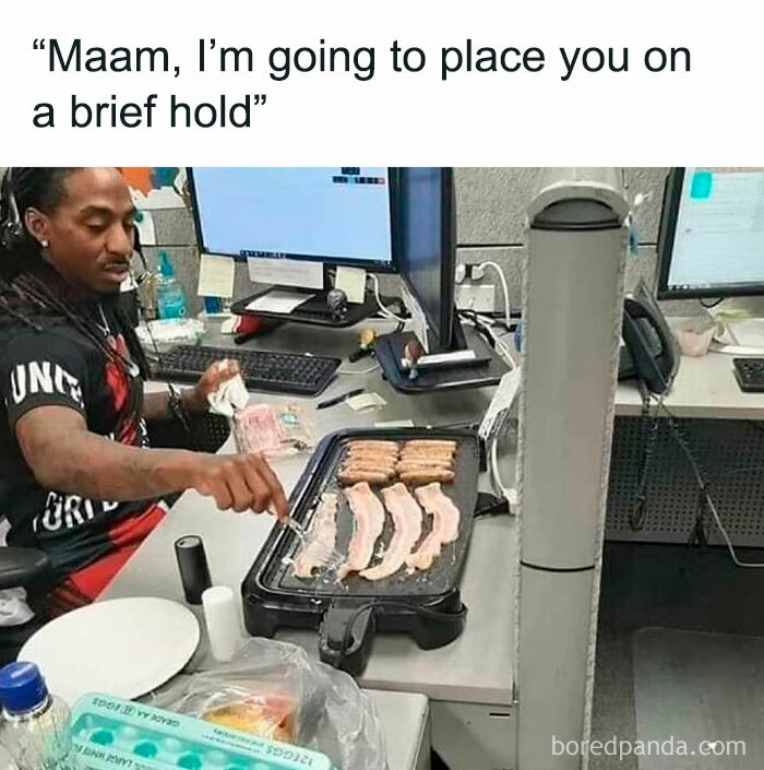 Office worker cooking bacon on a griddle at a desk, illustrating funny office meme.