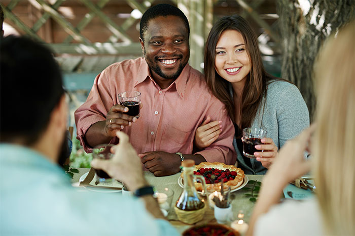 Friends at an outdoor gathering, smiling and holding drinks, casually dressed amidst a relaxed setting. Friends at an outdoor gathering, smiling and holding drinks, casually dressed amidst a relaxed setting.