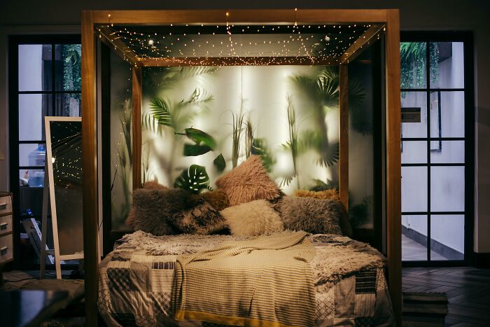Cozy bed with fluffy pillows and a canopy, surrounded by plants, creating an improved and inviting bedroom atmosphere.