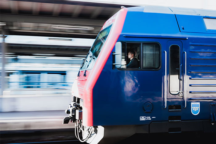 Train conductor operating a blue and red train, showcasing a high-earning profession in transportation.