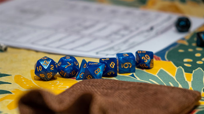 Blue dice on a colorful tablecloth next to a paper sheet, representing a game setting for people who earn $10K monthly.
