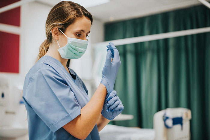 Healthcare professional in scrubs and mask prepares for work, demonstrating roles of people who earn above $10K monthly.