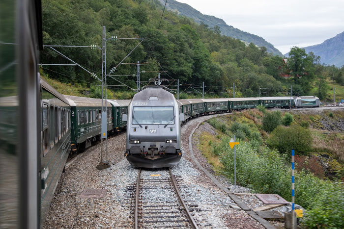 Train traveling through a lush, mountainous landscape, showcasing scenic routes and beautiful views of nature.