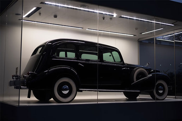 A classic black vintage car displayed in a modern showroom under spotlights.