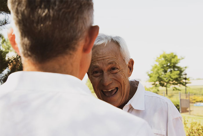 Two people in white shirts having a lively conversation outdoors, discussing what they do for a living.