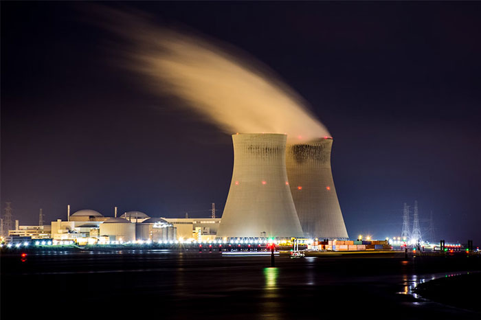 Nuclear power plant at night with cooling towers and lights, related to high-earning careers.
