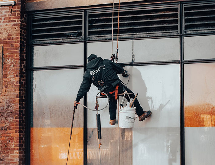 A person in safety gear cleaning windows, representing high-earning jobs.