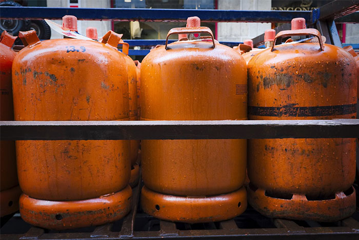 Orange gas cylinders lined up in storage, representing industrial work environments.