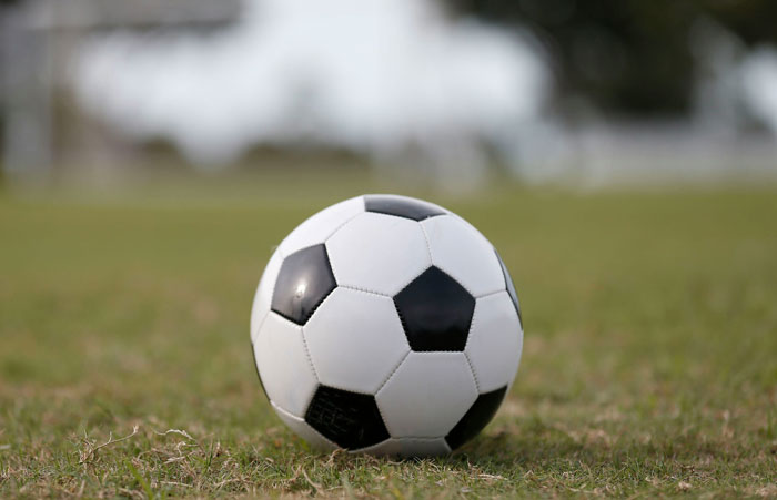 Soccer ball resting on grass field symbolizing people who survived due to another’s sacrifice stories.