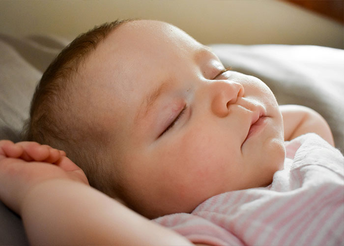 Sleeping baby lying peacefully on a bed, symbolizing tranquility amidst family tensions involving a Canadian woman. Sleeping baby lying peacefully on a bed, symbolizing tranquility amidst family tensions involving a Canadian woman.
