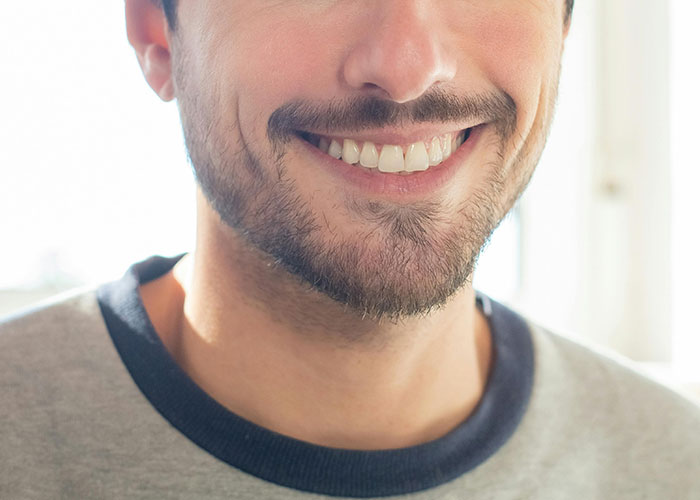 Smiling man with a beard in a casual shirt, symbolizing awkward job interviews.