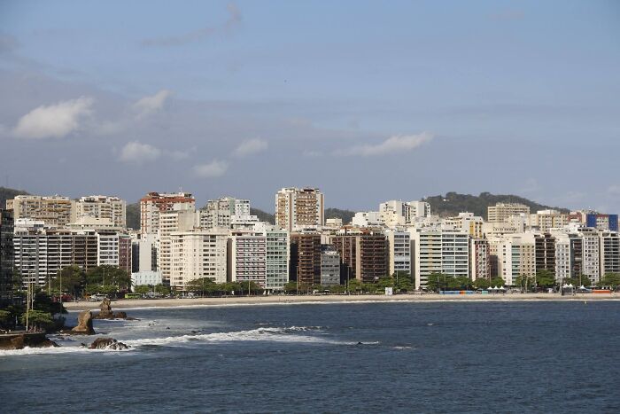 Coastal cityscape with tall buildings by the sea, under a clear sky, related to unsolved mysteries.