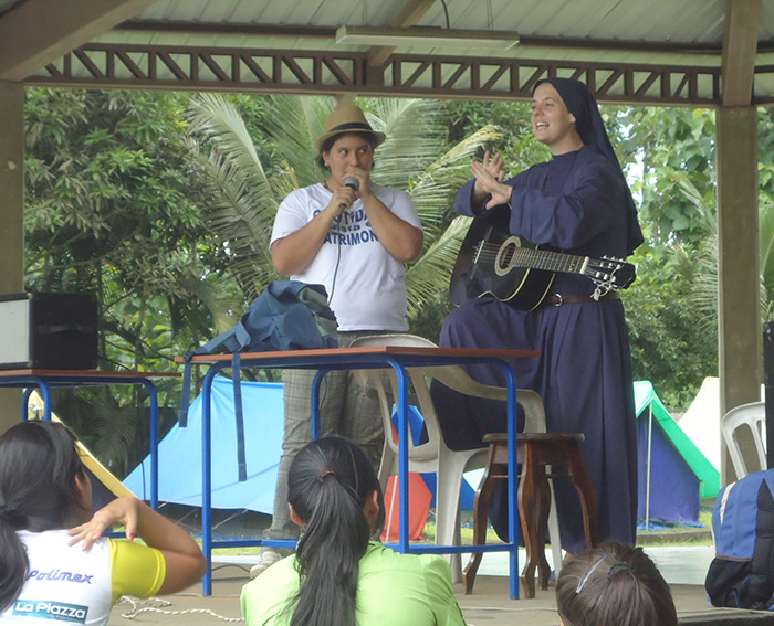Sister Clare Crockett with a guitar engaging with a crowd during an outdoor event. Sister Clare Crockett with a guitar engaging with a crowd during an outdoor event.