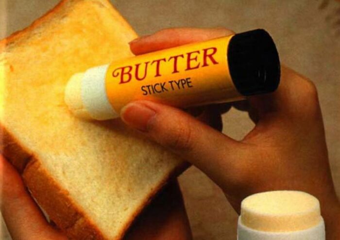 A person applies butter with a stick-type applicator on toast, showcasing historical inventions ahead of their time.
