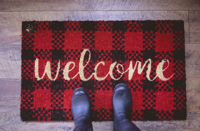 Welcome mat with red and black plaid design.