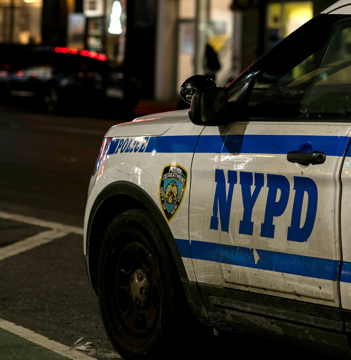 NYPD police car parked on a city street at night, highlighting issues of officer corruption.