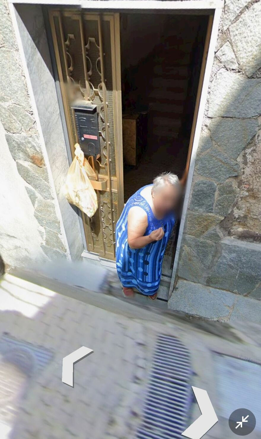 Person in a blue dress at a doorstep, captured on Google Earth.