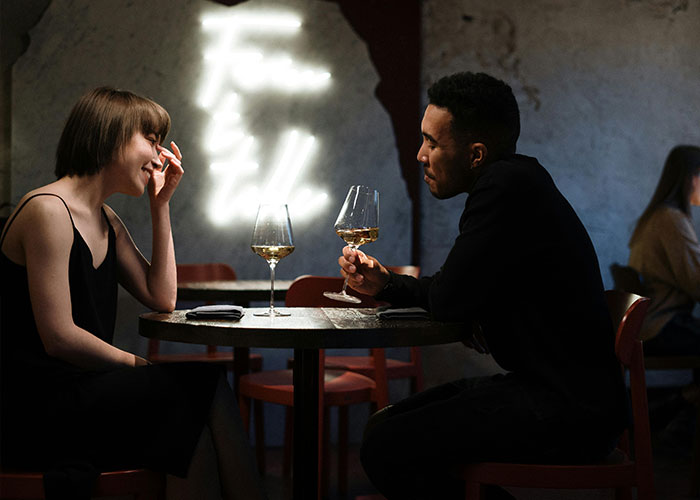 A couple sharing a conversation over wine, highlighting "he's different" moments in a cozy setting.
