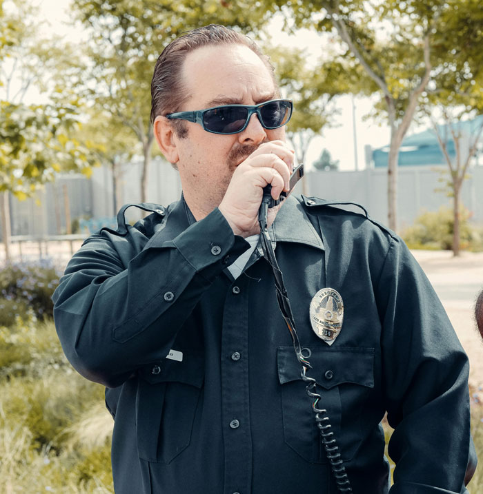 Police officer in uniform speaking through a radio, symbolizing corruption issues in law enforcement.