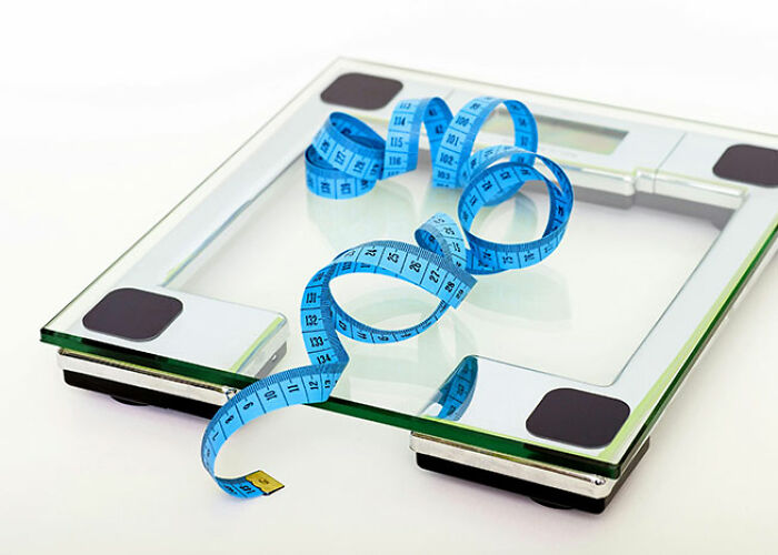 Glass scale with blue measuring tape, showcasing a life hack for weight tracking.