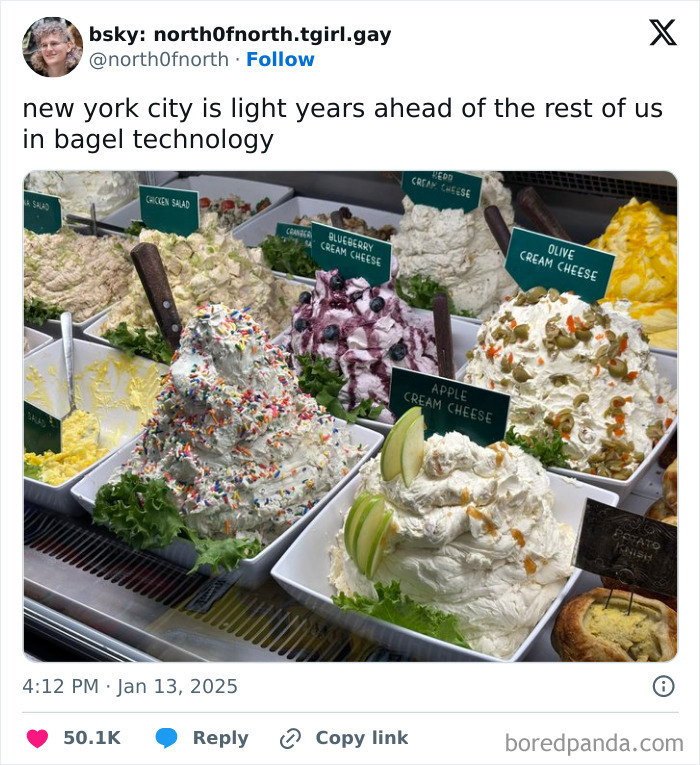 A variety of cream cheeses with toppings, such as apple slices, sprinkles, and olives, displayed at a deli counter in New York City.