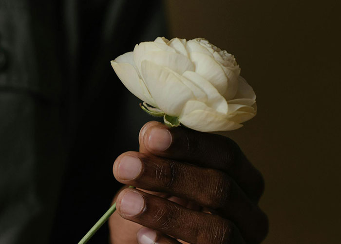 Man holding a white flower, showcasing something different and unique.