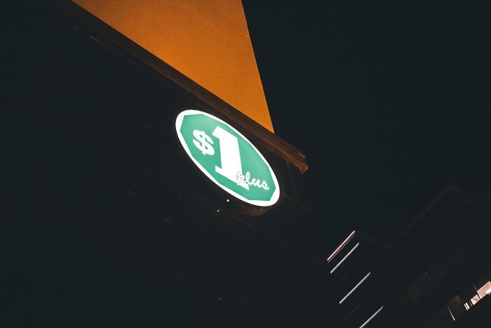 Sign with $1 symbol illuminated at night, reflecting financial stereotypes.