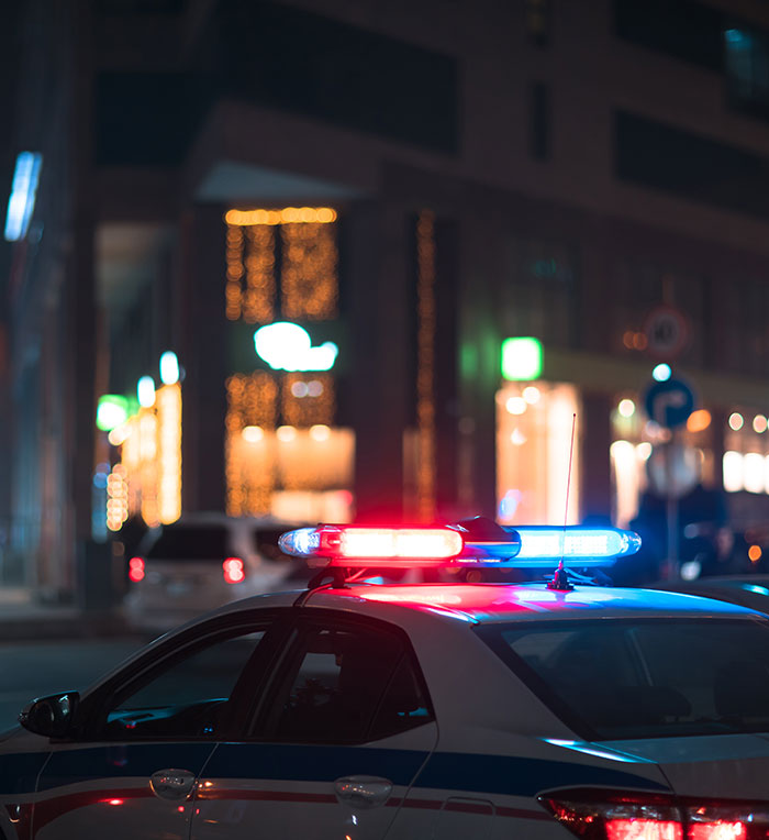 Police car with flashing lights outside a hotel at night.