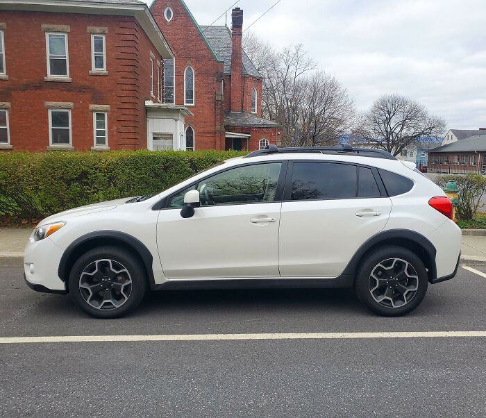 White SUV parked on street in front of brick building, illustrating what men shouldn't be judged for.