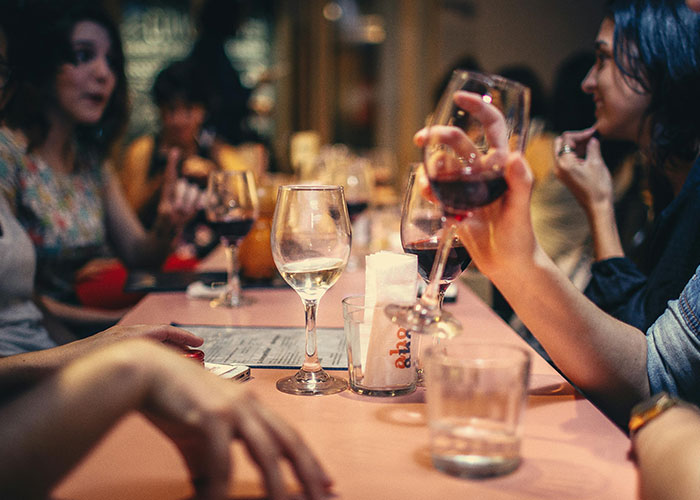 People socializing at a table with wine glasses, emphasizing conversation and connection. People socializing at a table with wine glasses, emphasizing conversation and connection.
