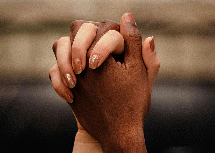 Hands clasped together, displaying unity and connection, representing the theme "wow, he's different."