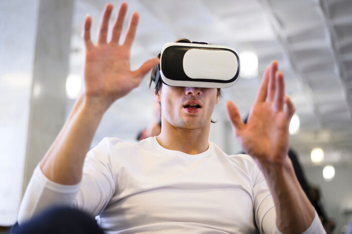 Person wearing VR headset, interacting with virtual technology.