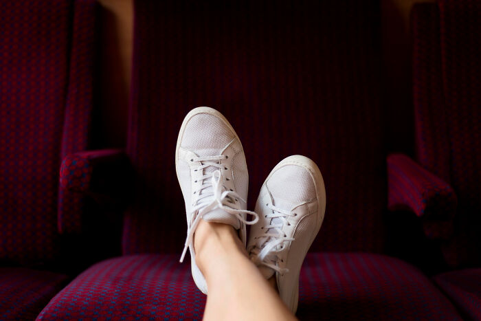 White sneakers resting on red patterned seats, depicting a casual home rule scenario.