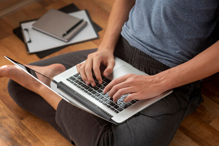 Person using a laptop on the floor, exemplifying reluctance of older people towards modern technology.