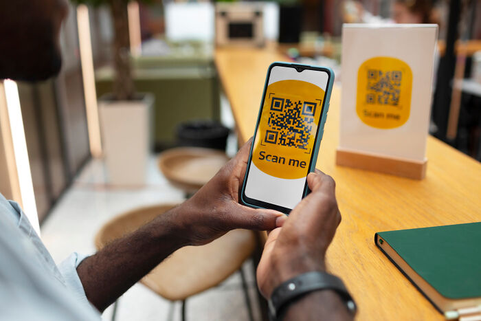 Person using a smartphone to scan a QR code in a modern setting, highlighting modern technology.