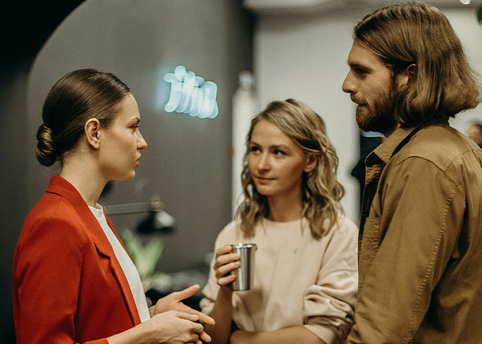 Three people engaged in conversation at a social gathering, showcasing a unique moment with someone different.