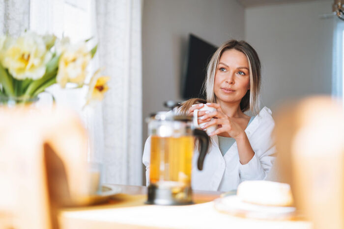 Woman enjoying tea at home, reflecting on strict house rules.