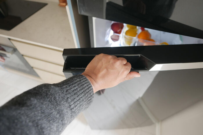 Hand opening a modern fridge door, reflecting on technology older people refuse to use.