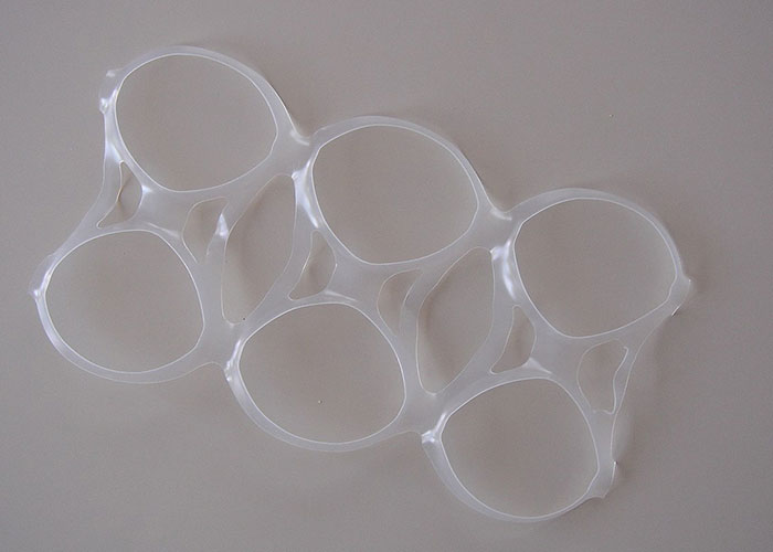 Plastic six-pack ring laid flat on a neutral surface, showing its structure and design.